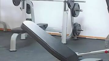 Un gimnasio con equipo de ejercicio, incluyendo una banca y máquinas de pesas.