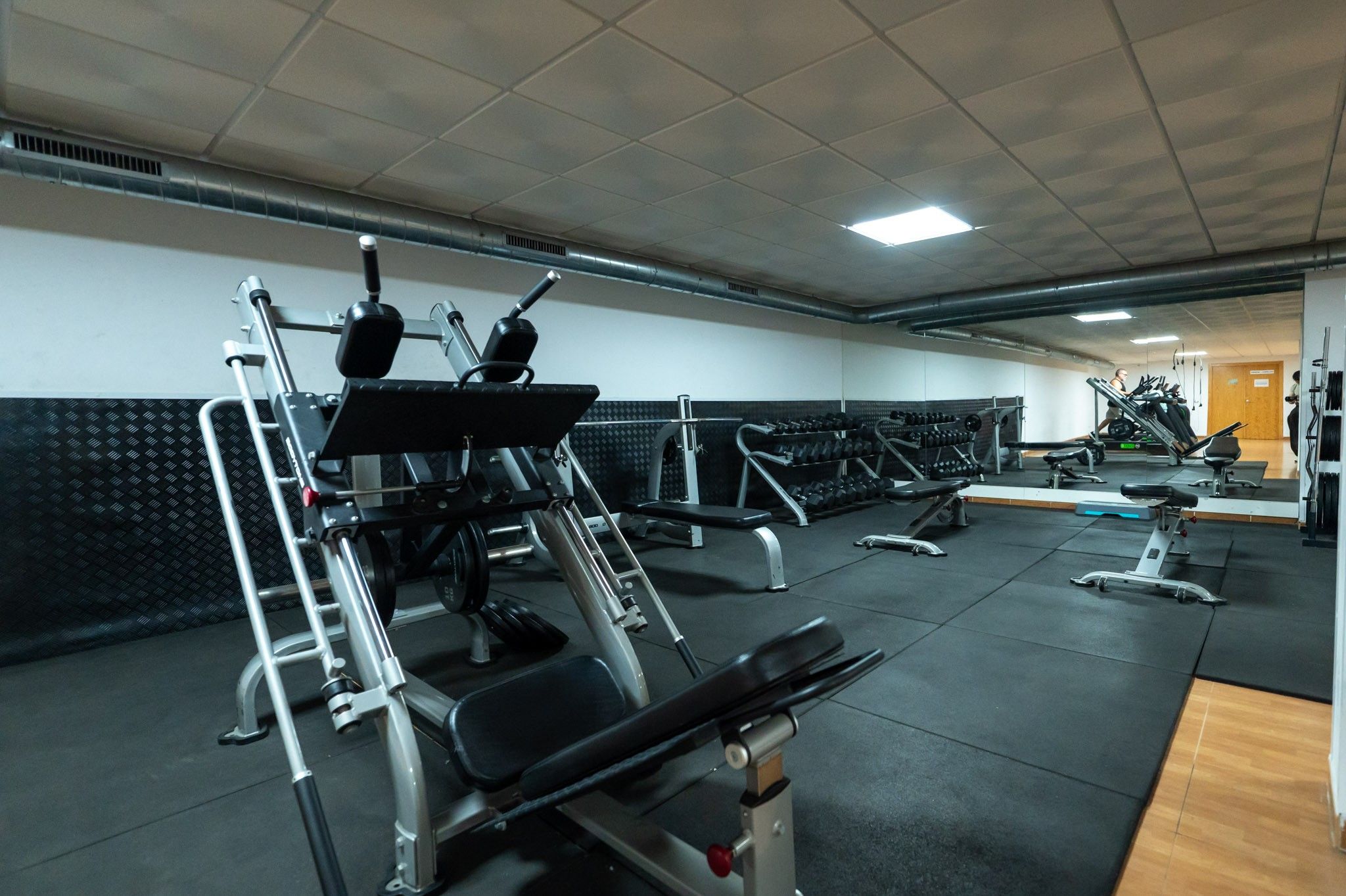 A gym with various exercise equipment, including treadmills, weight machines, and free weights.
