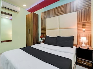Habitació d'hotel amb llit, taula de nit, làmpada i aire condicionat.