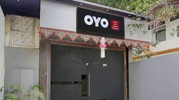 A hotel entrance with a closed shutter, a signboard with the name 'OYO Hotel Blue Sapphire Residency', and a decorative garland above the entrance.
