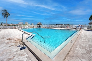 A rectangular swimming pool with a clear blue water surface, surrounded by a tiled deck and a white fence. - Relaxed Island Living Condo Golf Course Views (St.Petersburg)