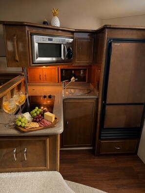 A compact kitchen with a microwave, a sink, and a refrigerator.