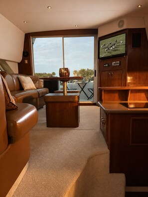 A modern living area with a leather sofa, a wooden coffee table, and a television mounted on the wall.
