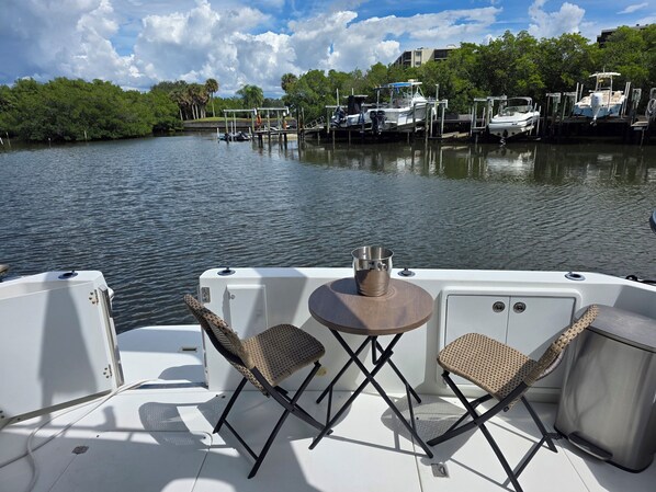 A boat deck with two chairs, a table, and a metal bucket.