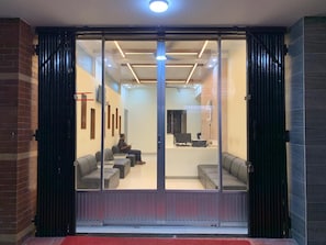 A modern interior with a reception desk, seating area, and a glass door entrance. - Hotel Al Barakah (Sylhet)
