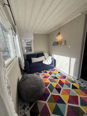 Une pièce chaleureuse avec un canapé bleu, un tapis géométrique aux couleurs vives et un sol orné de motifs en forme d’étoiles.
