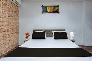 Quarto de hotel com cama, mesa de cabeceira, abajur e um quadro na parede.