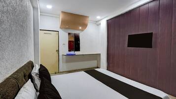 A hotel room with a bed, a small desk, a mirror, and a wardrobe.