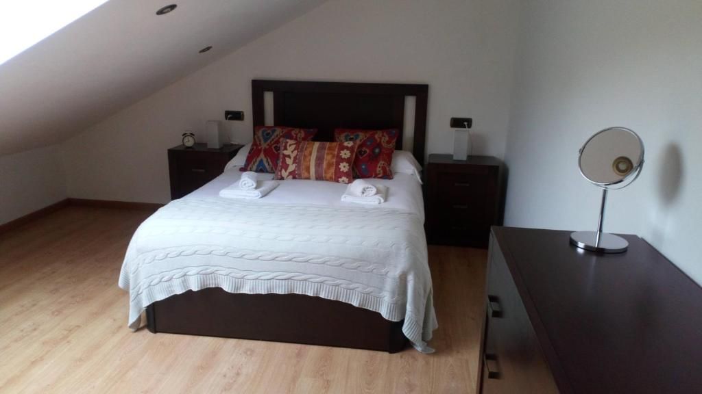 Een slaapkamer met een bed, twee nachtkastjes, een lamp en een houten vloer.