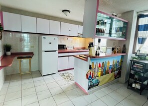 Eine Küche mit weißen Schränken, einem Kühlschrank, einer Mikrowelle und einer Kaffeestation.