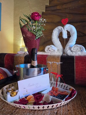 A table with a bouquet of flowers, a bottle of champagne, a card, and a tray of assorted fruits. - New Listing (Orgaz)
