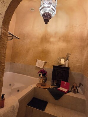 A bathroom with a bathtub, a towel rack, a potted plant, a small cabinet, and a decorative item. - New Listing (Orgaz)