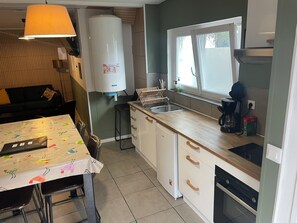 Una cocina compacta con un lavamanos, una cafetera y un calentador de agua grande.