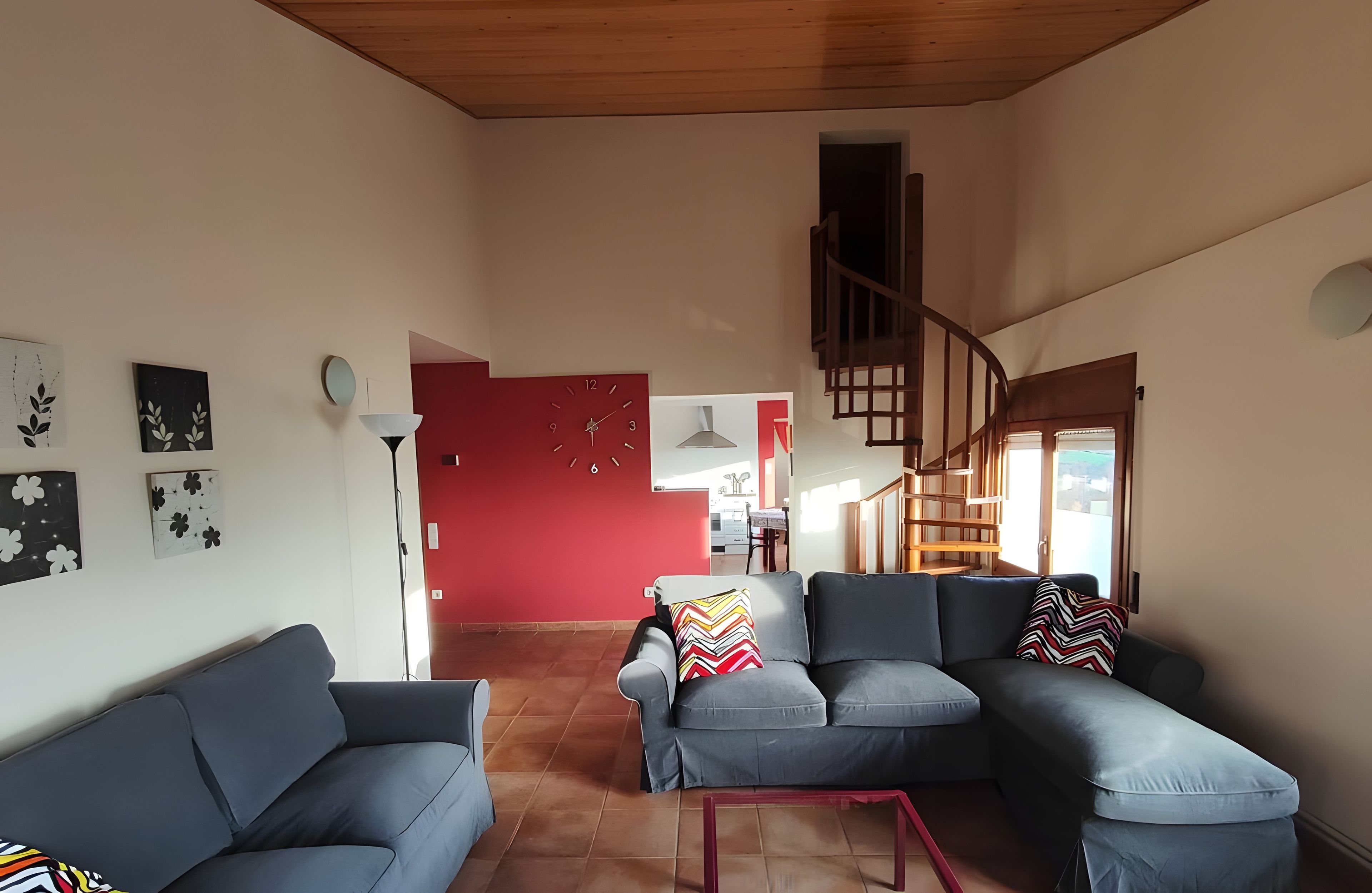 Una sala moderna con una pared de acento roja, una escalera y vistas al comedor.