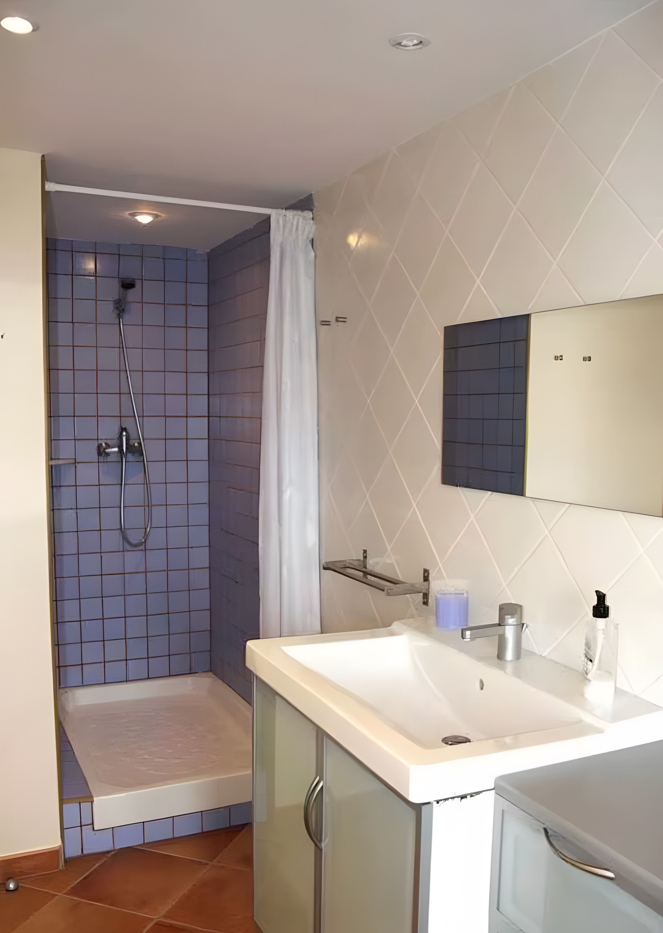 A bathroom with a shower, a sink, and a mirror.