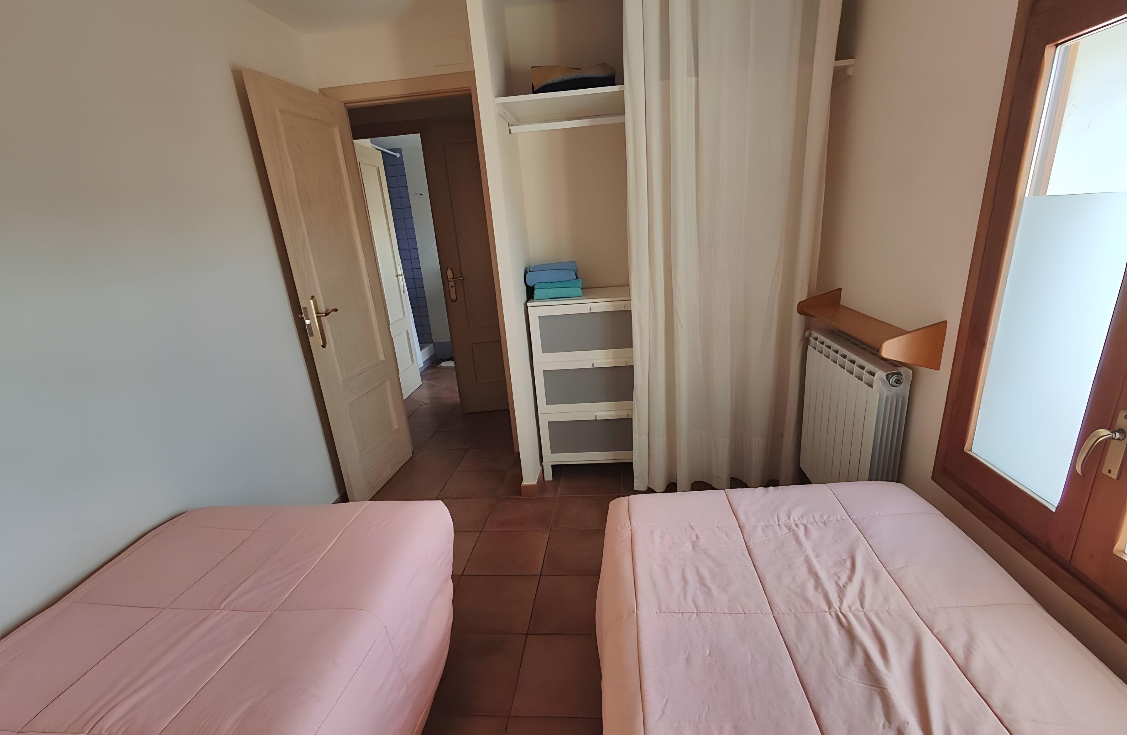 Een kamer met twee bedden, een kledingkast en een radiator.