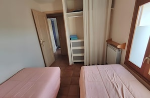 A room with two beds, a wardrobe, and a radiator.
