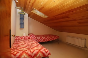 Ein Schlafzimmer mit zwei Betten, einer Holzbalkendecke und einer Heizung.