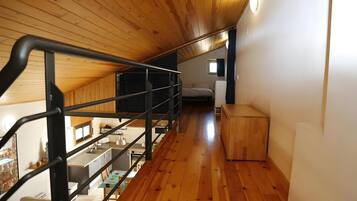 A wooden staircase leading to a bedroom with a bed and a small window.