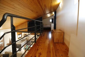 A wooden staircase leading to a bedroom with a bed and a small window.