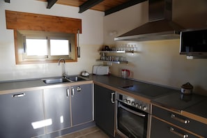 Eine moderne Küche mit Edelstahlgeräten, Holzbalken und einem Fenster.