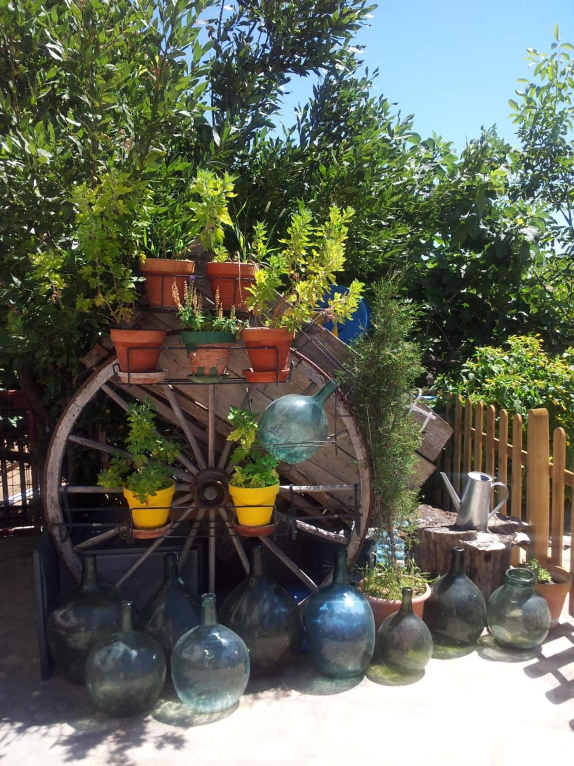 Una noria decorativa con macetas y botellas de vidrio.