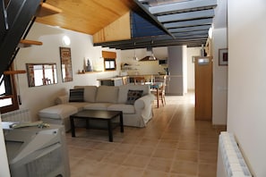 A modern living room with a sofa, a coffee table, and a kitchen in the background.