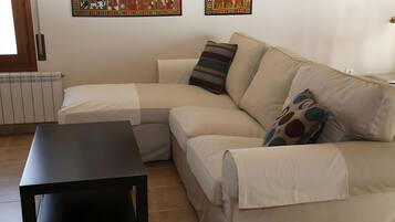 A living room with a sectional sofa, a small table, and two wall-mounted artworks.