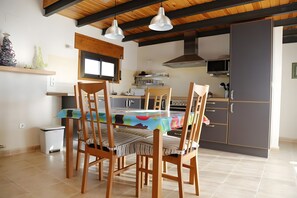 A kitchen with a dining table, chairs, and a refrigerator.