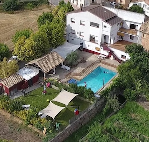 A residential area with a swimming pool, a covered outdoor seating area, and a fenced yard.