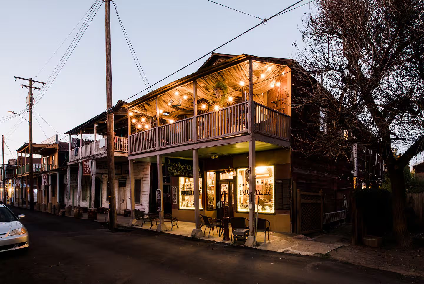 A two-story building with a balcony, outdoor seating, and a sign for 'Locke's.'