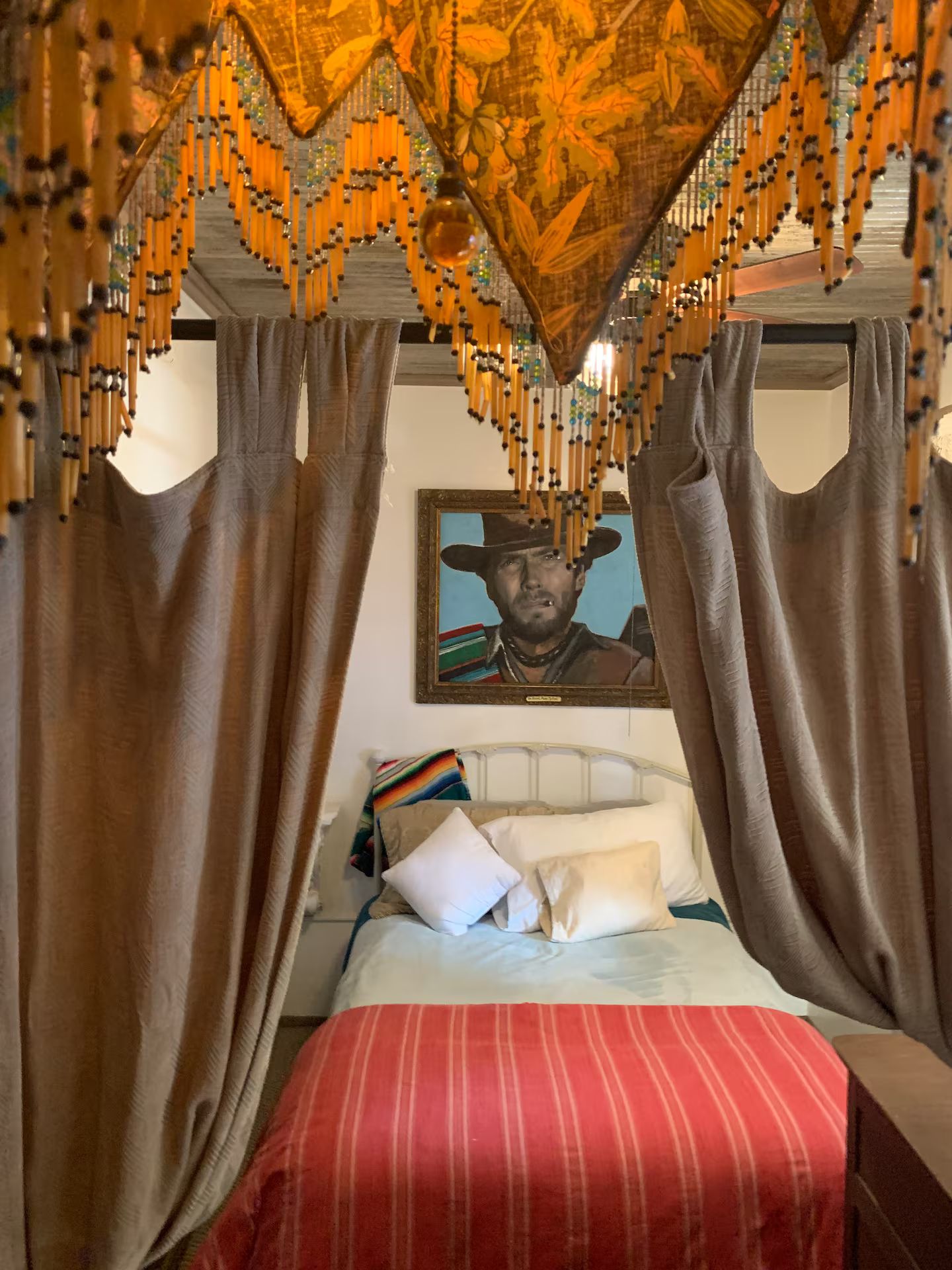A bed with a red-striped bedspread, a white pillow, and a colorful blanket.