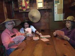 Three individuals seated at a wooden table playing cards.