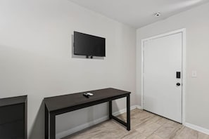 Een kamer met een donker houten tafel, een witte deur en een wandgemonteerde flatscreen televisie.