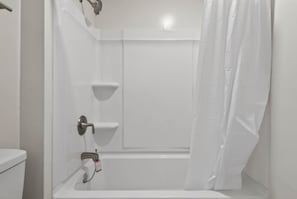 A white bathroom with a shower, toilet, and a towel rack.