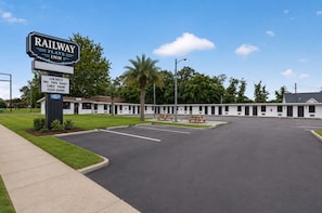 Een Railway Flats Inn met een duidelijk bord, een parkeerplaats en een rij motelkamers.