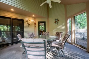A covered patio with a glass table and chairs, large windows, and ceiling fans. - Spacious Family Getaway with Amenities + Pool Access (Galena)