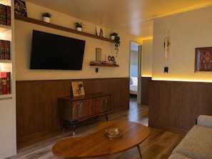 A living room with a flat-screen TV, wooden cabinet, and a round coffee table. - Pandora Residences  (Ciudad de México)