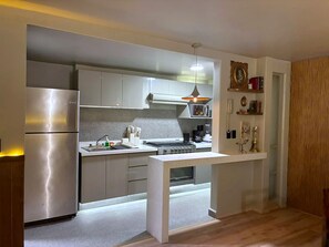 A modern kitchen with a built-in oven, a refrigerator, and a microwave. - Pandora Residences  (Ciudad de México)