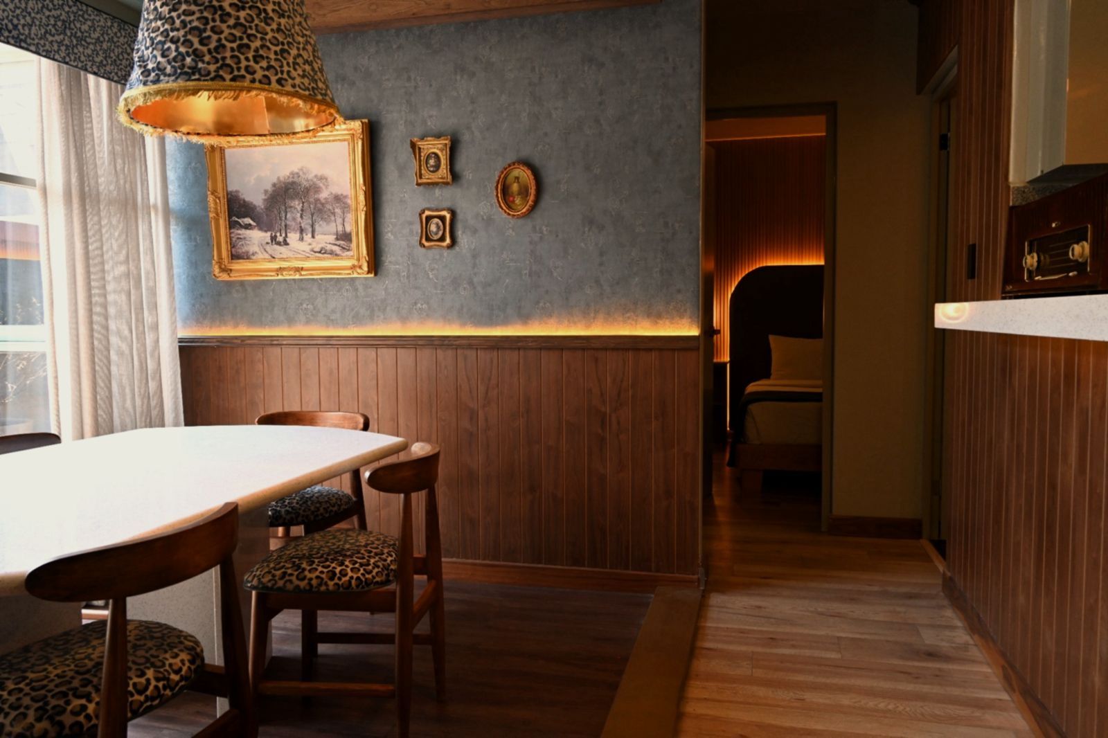 Un comedor con mesa y sillas de madera, una lámpara con diseño y cuadros en la pared.