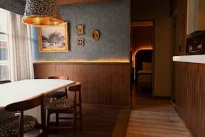 Un comedor con mesa y sillas de madera, una lámpara con diseño y cuadros en la pared.