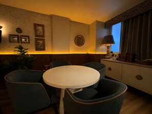 A dining area with a round table and four chairs, a mirror, framed pictures on the wall, and a window with curtains. - Pandora Residences  (Ciudad de México)
