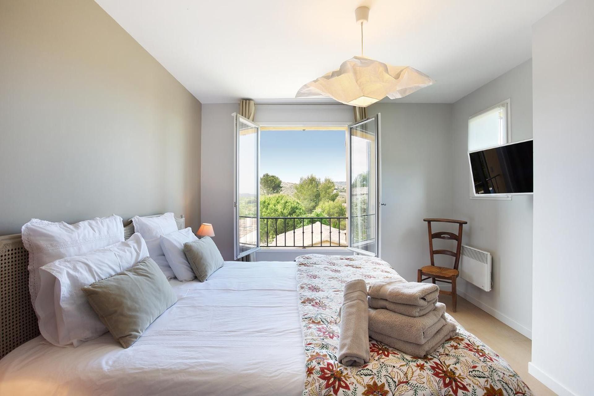 Ein Schlafzimmer mit einem Bett, einem Fenster, einem Sessel und einem Fernseher an der Wand.