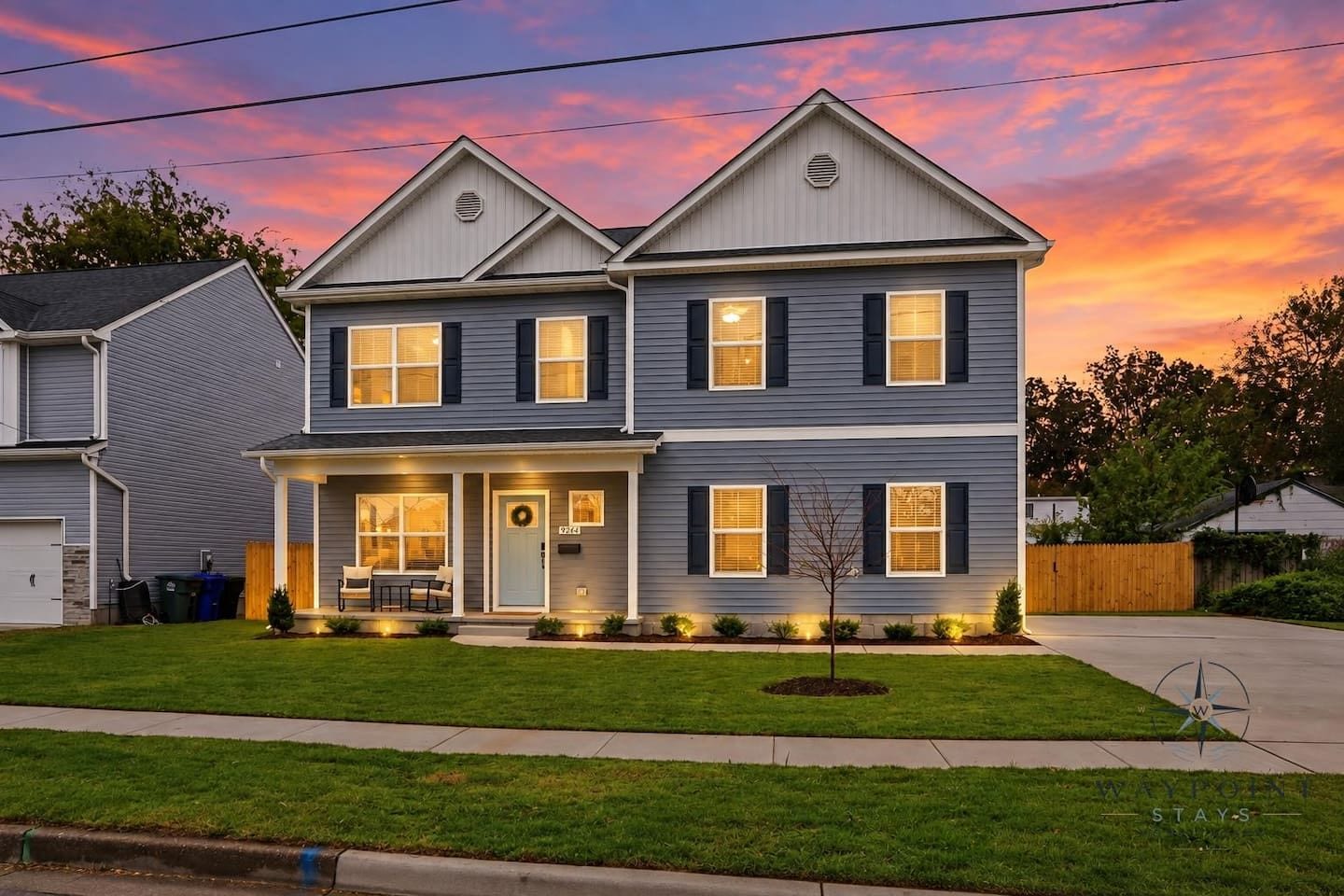 A two-story residential house with a front porch, a garage, and a well-maintained lawn.