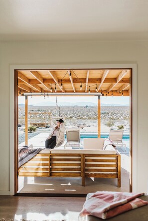 Una habitación con techo de madera, una hamaca y vistas a un paisaje desértico.