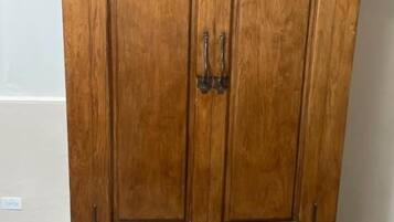 A wooden wardrobe with two doors and three drawers, featuring ornate handles and a decorative top.