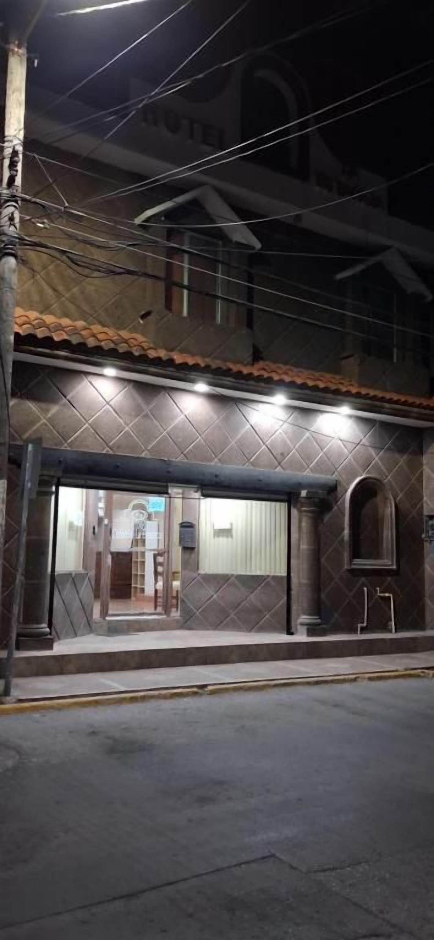 Un edificio con techo de tejas, una entrada visible y un cartel que indica que es un hotel.