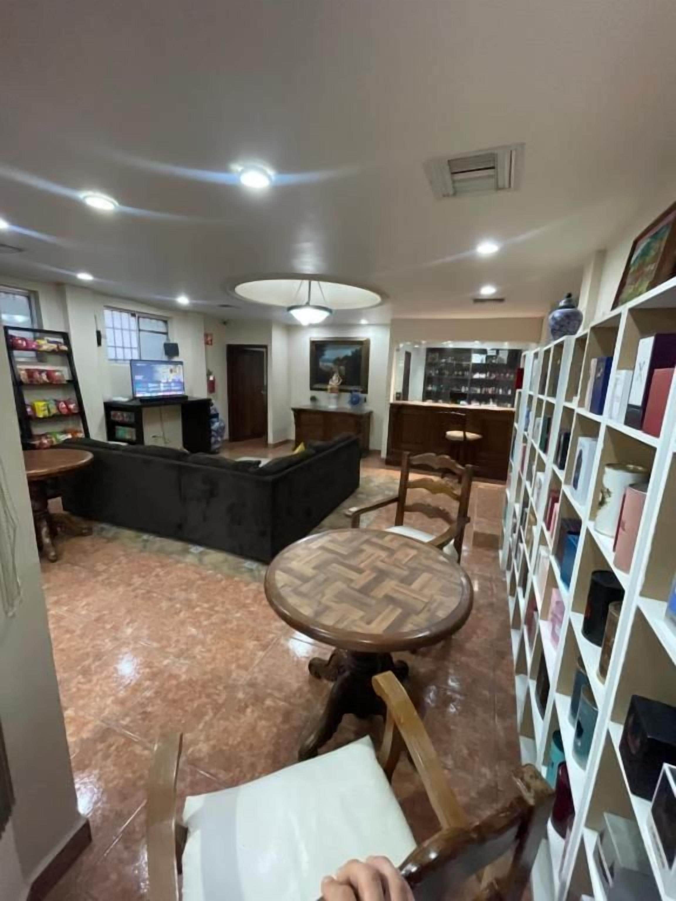 Un vestíbulo de hotel con una mesa redonda de madera, una estantería y un televisor.
