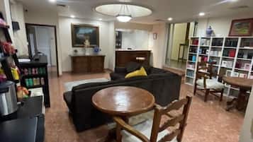 Una sala de estar con sofá, una mesa de comedor y una zona de cocina con electrodomésticos.