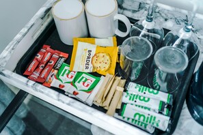 Ein Tablett mit verschiedenen Speisen, darunter Nescafe-Tütchen, eine Kekspackung und eine Tasse.